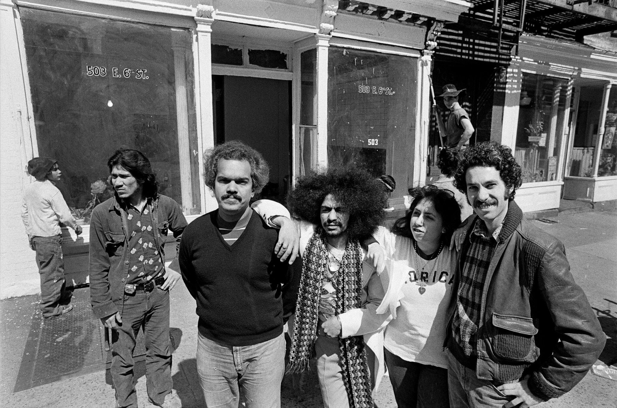 Miguel Algarín, wearing a V-neck, with fellow poets outside the Nuyorican Poets Cafe in 1976.